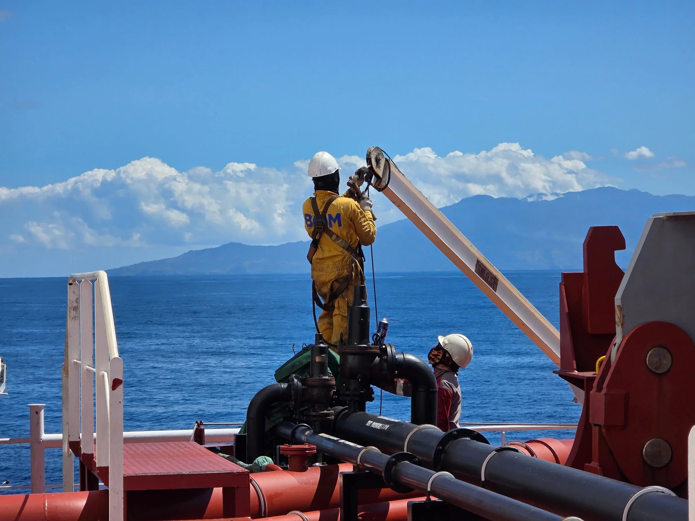 Marine personnel operating deck equipment in protective workwear